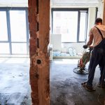 Mann benutzt elektrische Kellenmaschine auf der Baustelle.